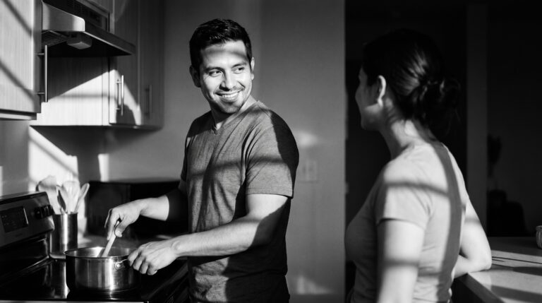 A man cooking dinner at home and smiling warmly at the woman beside him